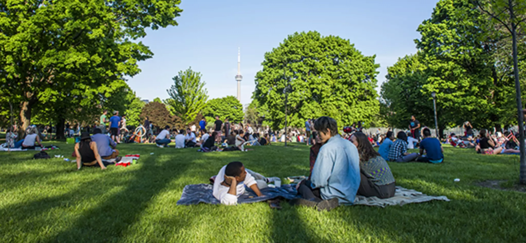 Toronto residents enjoy summer afternoon in park with CN Tower in background